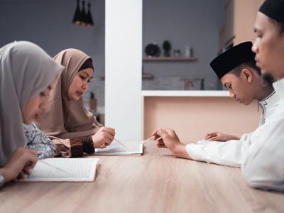 portrait of happy muslim family reading quran or holy book of islam together