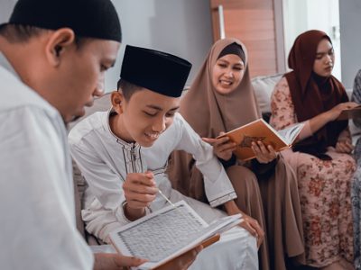 portrait of muslim family reading quran together in livingroom